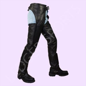 May include: Black leather motorcycle chaps with a buckle closure at the waist and snap closures at the bottom of the legs. The chaps are shown over a pair of light blue jeans and black boots.