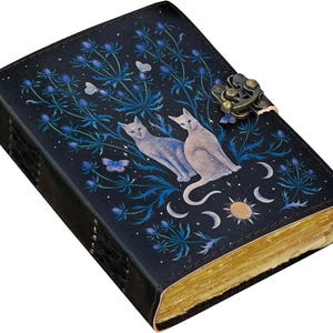 Puede incluir: Un diario azul oscuro con un dise&ntilde;o decorativo que presenta dos gatos, mariposas y elementos celestiales. La cubierta tiene un cierre de metal y las p&aacute;ginas tienen un borde dorado. El diario es un art&iacute;culo &uacute;nico para escribir y llevar un diario.