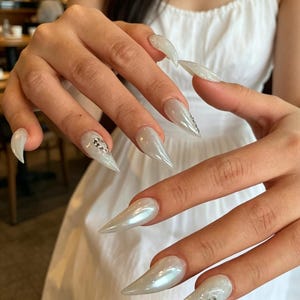 Puede incluir: Una taza de cerámica blanca con un asa negra y el texto "But First, Coffee" en negro, con una fuente de estilo manuscrito. La taza está sobre una superficie blanca.