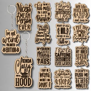 May include: A collection of light-colored wooden keychains featuring dark engraved text with humorous phrases such as Nicest Mean Person Ever, I'm Not A Hot Mess, My Brain Has Too Many Open Tabs, and I Put The Pro In Procrastinate, each with a metal ring.