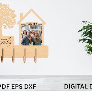 Puede incluir: Llavero de madera con diseño de árbol, un marco de fotos en forma de casa y el texto "Home is not a place it's a feeling". Incluye cinco ganchos para llaves. Una foto familiar se muestra en el marco.