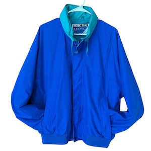May include: A blue Pacific Trail Active jacket with a teal collar and lining. The jacket has a zipper closure, two front pockets, and a ribbed hem and cuffs. The Pacific Trail logo is visible on the collar.