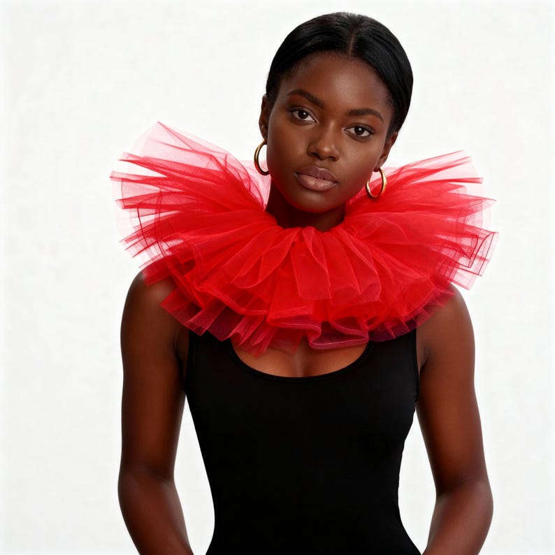 May include: A vibrant red tulle collar, layered and ruffled, is the focal point. The collar is worn over a black top. The model is wearing gold hoop earrings. The background is plain white.