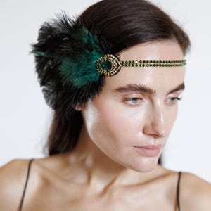 Peut inclure: Un bandeau de style Charleston orné de plumes noires et vert émeraude. Le bandeau est orné d'un bijou central circulaire avec une pierre verte et de strass verts. Accessoire pour un look vintage ou sur le thème Gatsby.