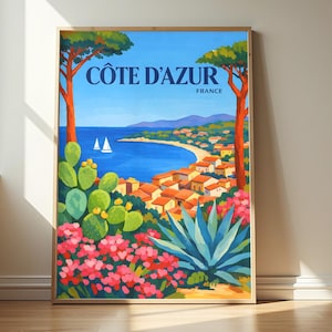Könnte beinhalten: Ein vertikales Reiseplakat mit dem Titel CÔTE D'AZUR FRANCE, das eine Küstenlandschaft mit blauem Meer, zwei weißen Segelbooten, einer Stadt mit orangefarbenen Dächern, hohen Pinien, grünen Feigenkakteen und rosa Blumen zeigt.