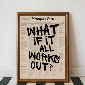 Peut inclure: Une impression encadrée présentant une page de journal au style vintage avec le texte noir, audacieux et manuscrit WHAT IF IT ALL WORKS OUT? superposé sur des colonnes de petit texte illisible, le tout dans un cadre en bois brun simple.
