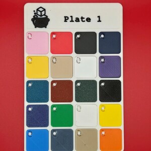 May include: A white rectangular color palette labeled "Plate 1" with a cauldron and cube logo. It features 16 small, square color swatches in various colors, including pink, red, black, navy, yellow, beige, white, and purple.