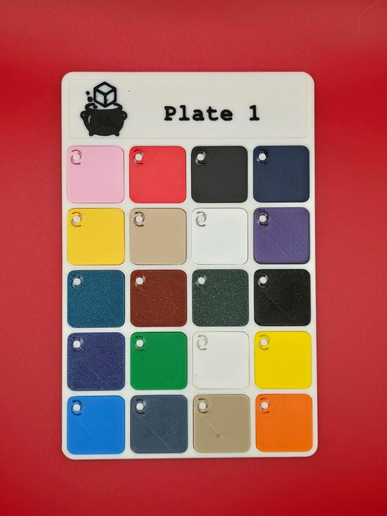 May include: A white rectangular color palette labeled "Plate 1" with a cauldron and cube logo. It features 16 small, square color swatches in various colors, including pink, red, black, navy, yellow, beige, white, and purple.