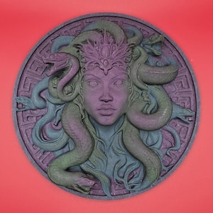 May include: A circular relief sculpture of Medusa with snakes for hair, in shades of purple, green, and blue. The Medusa figure has a crown and is set against a patterned border. The background is a solid red.