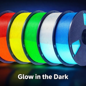 May include: Spools of glow-in-the-dark 3D printing filament in red, orange, yellow, green, white, and blue. The image includes a glowing blue deer silhouette and the text "Glow in the Dark".