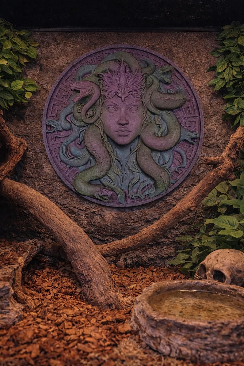 May include: A circular wall relief sculpture of Medusa in shades of purple, green, and blue. The sculpture is surrounded by a textured stone wall, with branches, leaves, and a skull in the foreground. The Medusa sculpture is the focal point.
