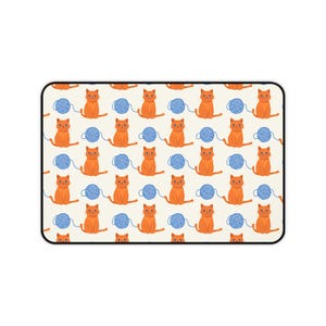 Peut inclure: Un tapis de souris rectangulaire avec un motif répété de chats orange et de boules de fil bleues sur un fond crème. Les chats sont assis, et les boules de fil sont rondes.