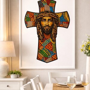 May include: Framed artwork depicting a cross with a portrait of a man with a beard and long hair. The cross and portrait are decorated with colourful patchwork patterns in red, orange, green, and blue. The artwork is displayed in a white frame.