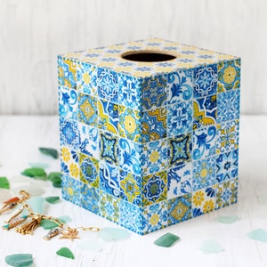 May include: A square tissue box cover with a colourful geometric pattern in shades of blue, yellow, and white. The pattern resembles traditional Portuguese tiles.