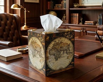 May include: A square wooden tissue box cover featuring a vintage world map print in shades of brown, cream, and gold. The box has ornate gold-toned metal corner accents and holds a stack of white tissues protruding from the top opening.