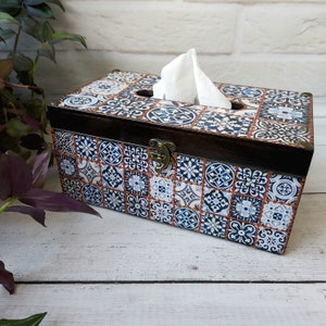May include: A wooden tissue box cover with a blue and white patterned design. The box has a hinged lid with a brass latch.
