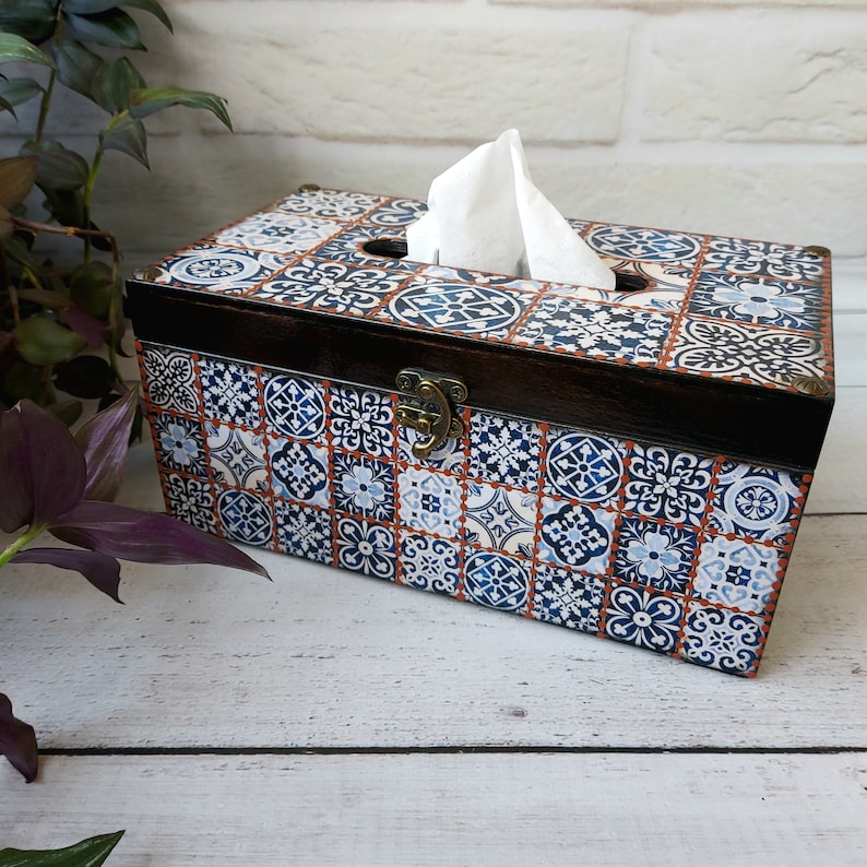 May include: A wooden tissue box cover with a blue and white patterned design. The box has a hinged lid with a brass latch.