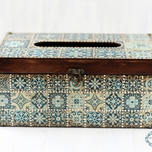May include: A wooden tissue box cover with a decorative design of blue and gold tiles. The box has a hinged lid with a metal clasp.