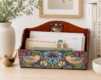 Op de afbeelding: Een houten bureau-organizer voor post met een donkerbruine afwerking en een voorpaneel versierd met een blauw, geel en rood bloemen- en vogelpatroon. De organizer bevat diverse enveloppen en een document met het opschrift INVOICE.