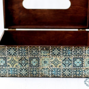 May include: A wooden tissue box cover with a decorative design of blue and gold tiles. The box is open and the inside is brown wood.