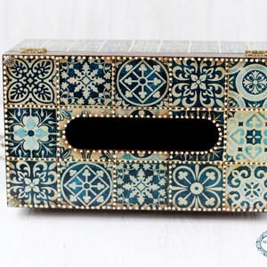 May include: A wooden tissue box cover with a blue and white tile pattern. The box has a rectangular opening for tissues and is decorated with gold accents.