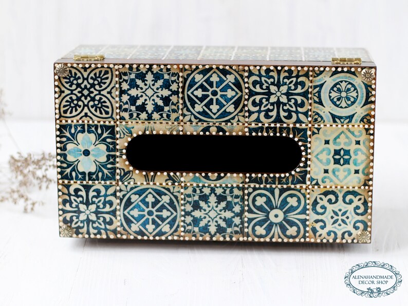 May include: A wooden tissue box cover with a blue and white tile pattern. The box has a rectangular opening for tissues and is decorated with gold accents.