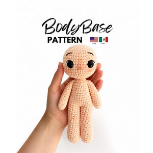 Puede incluir: Una muñeca de ganchillo de color melocotón claro con cabeza redonda, ojos de plástico negro y cejas bordadas. El texto BodyBase PATTERN aparece sobre la muñeca, acompañado de pequeños iconos de banderas estadounidense y mexicana.