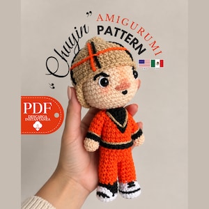 May include: A crochet amigurumi doll featuring a tan hat with orange accents, a peach-colored face, and an orange jumpsuit with black trim. The doll wears white shoes with black laces. Text on the image includes Chuyin Amigurumi Pattern and PDF.