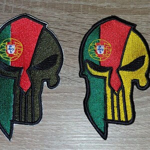 Pode incluir: Dois patches bordados em forma de caveira, cada um com as cores da bandeira portuguesa. Um patch tem um design verde e verde-oliva, enquanto o outro é verde e amarelo. Ambos apresentam o brasão de armas português.