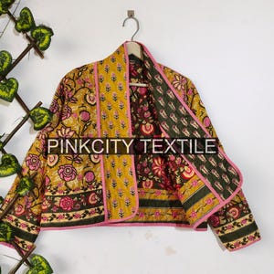 May include: A reversible jacket with a floral pattern in shades of yellow, pink, and green. The jacket has a pink trim and is hanging on a hanger. The text "PINKCITY TEXTILE" is visible.