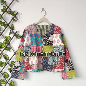 May include: A patchwork jacket with a V-neck and two pockets. The jacket features a variety of colorful floral and geometric patterns. The text "PINKCITY TEXTILE" is visible on the jacket.