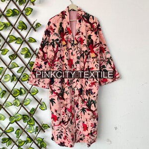 May include: A pink floral print robe with a bird and floral design. The robe has long sleeves and a belt. The text "PINKCITY TEXTILE" is printed on the bottom of the robe.