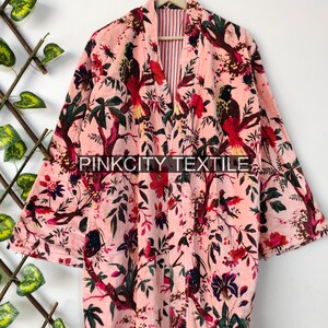 May include: A pink floral robe with a bird and tree design. The robe has long sleeves and a striped interior. The text "PINKCITY TEXTILE" is printed on the robe.