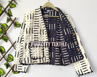 May include: Cream-coloured quilted jacket with a black geometric pattern. The jacket has a contrasting navy blue lining with a similar design. It features two front pockets and wooden buttons. The text "PINKCITY TEXTILE" is visible on the front.