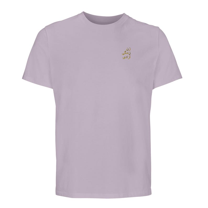 Puede incluir: Una camiseta de manga corta en color lavanda claro con un peque&ntilde;o bordado dorado en la parte superior izquierda del pecho. El bordado consta de tres l&iacute;neas de texto en persa, que se lee como: Zan, Zendegi, Azadi.