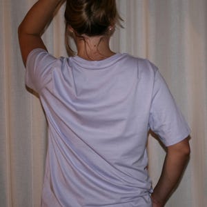 Puede incluir: Una camiseta de manga corta en color lavanda claro con cuello redondo. La prenda se combina con unos vaqueros de mezclilla azul. El tejido es liso y opaco, con un corte est&aacute;ndar, mangas cortas y un dobladillo recto en la parte inferior.