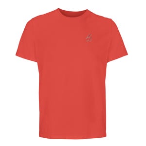 Puede incluir: Una camiseta de manga corta y cuello redondo en un color rojo coral s&oacute;lido. La prenda presenta un peque&ntilde;o bordado centrado en la parte superior izquierda del pecho que consiste en dos l&iacute;neas de texto en escritura &aacute;rabe de color plateado.