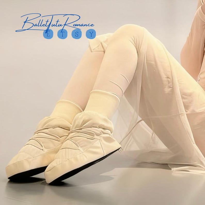 May include: Cream-colored ballet warm-up boots with black soles. The boots have a quilted design and are worn with matching leg warmers. The Etsy shop name "Ballet Tutu Romance" is in the upper left corner.