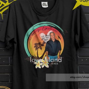 May include: Black t-shirt featuring a graphic with the text "love island" and a picture of a man. The design includes a heart, palm trees, and the text "Can I pull you for a chat?" The shirt is hanging on a black hanger.