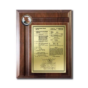 May include: A wooden plaque with a gold-colored patent document. The plaque has a dark brown finish and a circular emblem at the top left. The patent document includes text and a technical diagram.