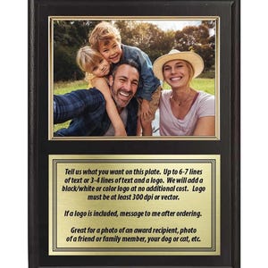 May include: A rectangular black wooden plaque featuring a top section with a color photograph of a family of four and a bottom section with a gold-colored metal plate containing black text instructions for custom engraving and personalization.