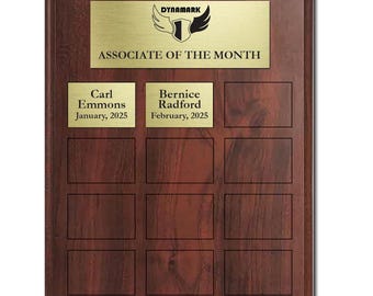 May include: A rectangular wooden plaque with a gold metal plate at the top that reads "DYNAMARK" and "ASSOCIATE OF THE MONTH". Below are two nameplates with names and dates, and nine empty nameplates. The plaque is brown.