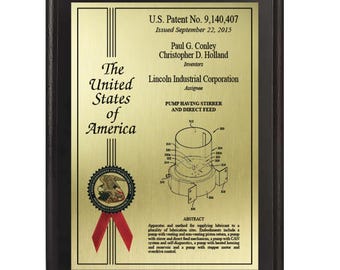 May include: A framed patent plaque with a gold-colored plate and black frame. The plaque displays the text "The United States of America" and patent information, including the patent number, issue date, and inventor names. A diagram of a pump is also visible.