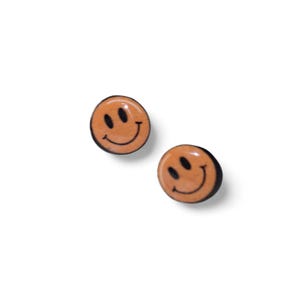 May include: Two orange smiley face stud earrings with black outlines. The earrings are round and have a glossy finish. The earrings are set against a white background.