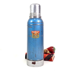 metallic blue and silver Stanley metal thermos, logo on front, aged patina