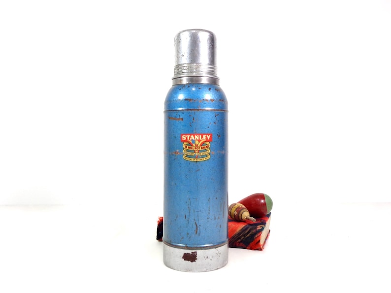 metallic blue and silver Stanley metal thermos, logo on front, aged patina