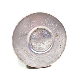 Pode incluir: Close-up da base de uma garrafa t&eacute;rmica Stanley Super Vac vintage. A base de metal prateado apresenta texto em relevo, incluindo "It will not break" e "Made in U.S.A.". As instru&ccedil;&otilde;es de uso tamb&eacute;m s&atilde;o vis&iacute;veis.