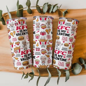 Pode incluir: Três canecas isoladas brancas com um padrão repetido de logotipos KFC, frango frito, hambúrgueres e o texto "KFC IS MY VALENTINE". As canecas são cilíndricas e têm uma tampa prateada. O design inclui corações vermelhos e ilustrações do mascote KFC.