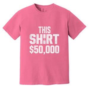 Puede incluir: Una camiseta rosa con el texto blanco "THIS SHIRT IS $50,000" en letras desgastadas. La camiseta tiene mangas cortas y cuello redondo. La tela parece ser una mezcla de algod&oacute;n suave.