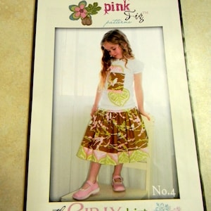May include: A sewing pattern for a girl's skirt, called "the girly skirt", from Pink Fig patterns. The pattern is number 4 and features a brown and green floral print skirt with a white top.